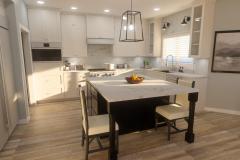 Kitchen area with white cabinetry and full marble backsplash