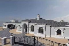 A grand Mediterranean-style estate with arched entryways, decorative columns, and a tiled roof is surrounded by a gated driveway and desert landscaping with palm trees and cacti.