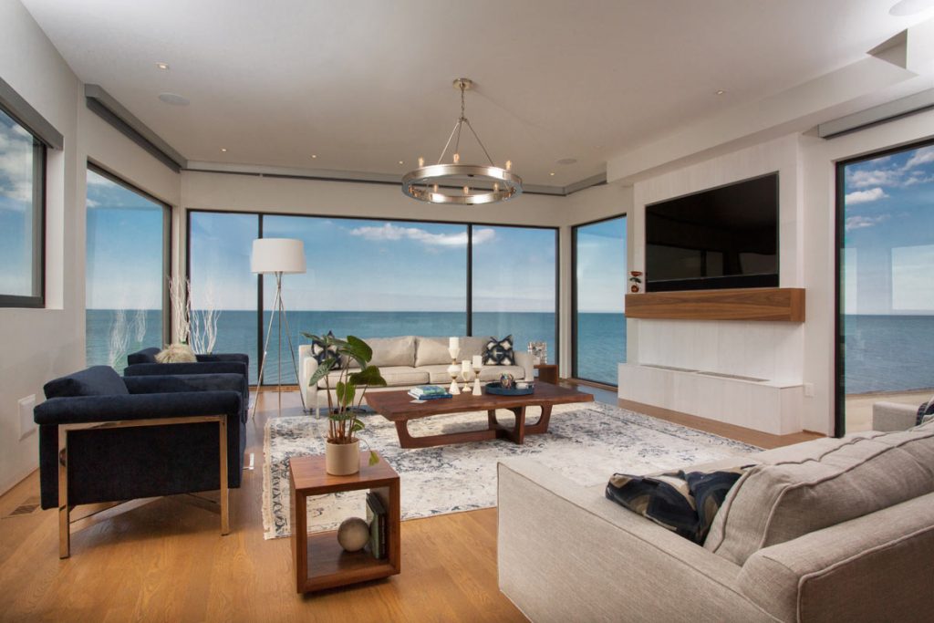 Bright living room with floor to ceiling windows exposing the ocean view.
