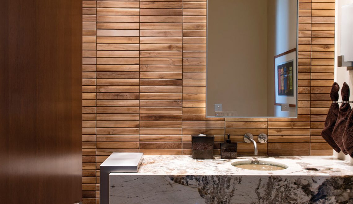 Warm colored teak wall tile and cool stainless steel of a vanity base are brought together with lively natural stone.