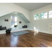 Large bonus room with light blue walls, white trim and hardwood floors.