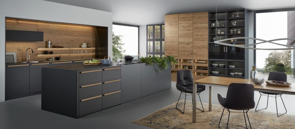 A modern kitchen with black cabinets and natural accents designed by Leicht.