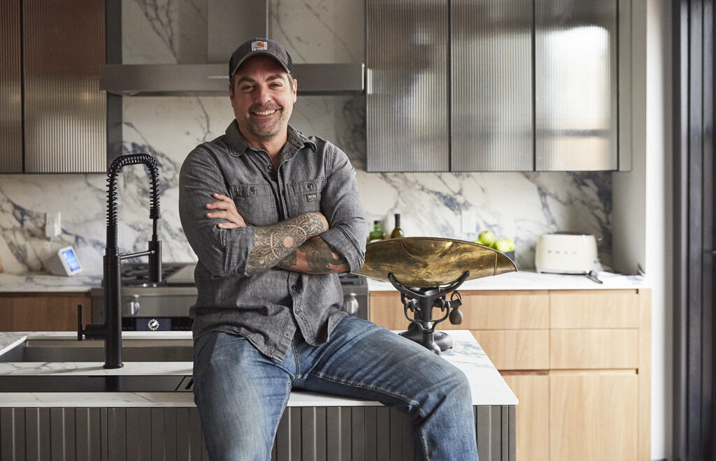 HGTV star, Anthony Carrino posing in finished kitchen renovation.