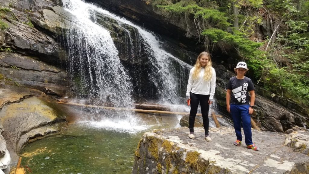 Kids posing in front of a waterfall they discovered while camping.