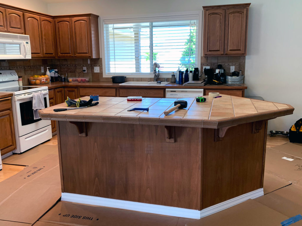 A kitchen with wooden cabinets and floors before the remodel process