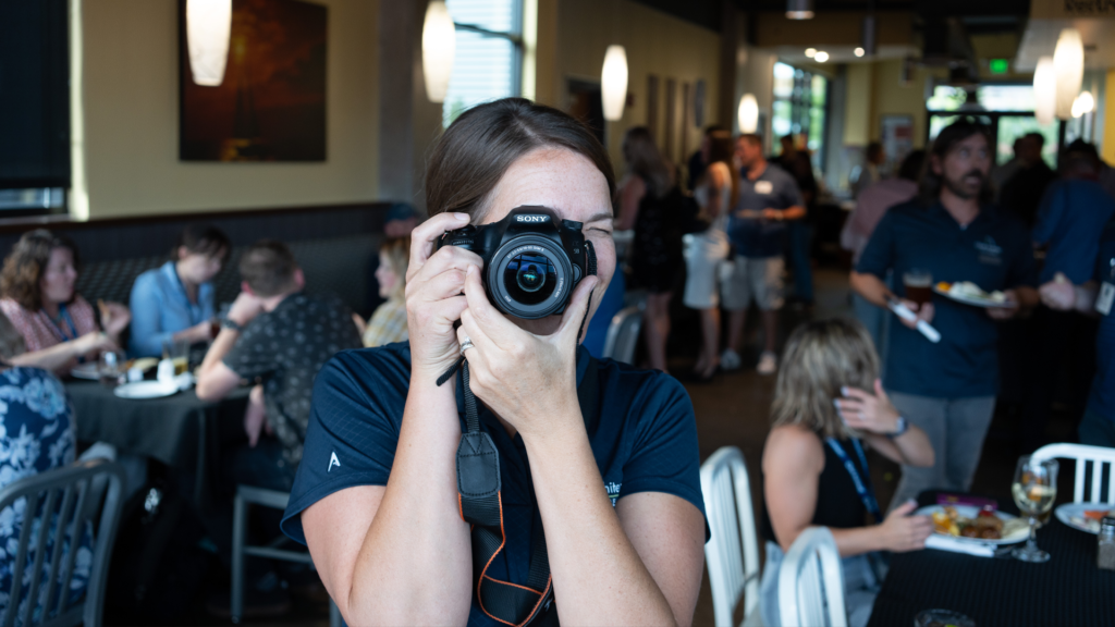 A social media manager holding a camera and collecting content to post.